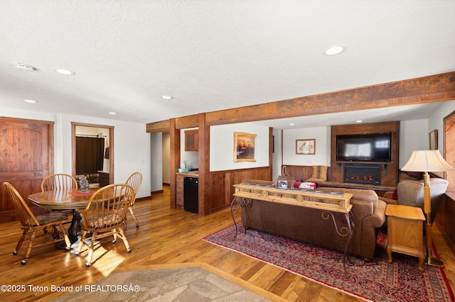 living room featuring hardwood / wood-style flooring, wooden walls, and a textured ceiling