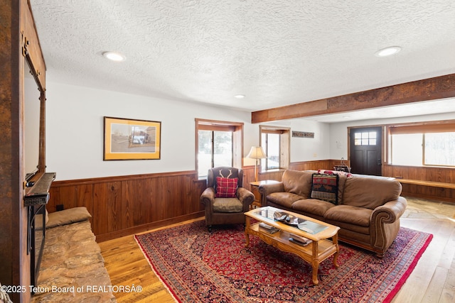 living room featuring wooden walls, light hardwood / wood-style floors, and a textured ceiling