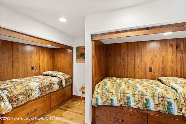 bedroom with wood walls and light hardwood / wood-style flooring