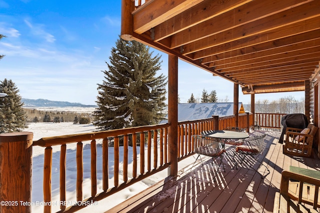 snow covered deck featuring a mountain view and grilling area