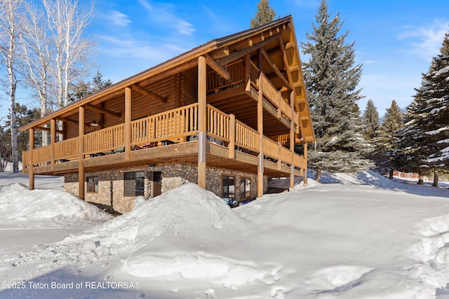 snow covered rear of property featuring a deck