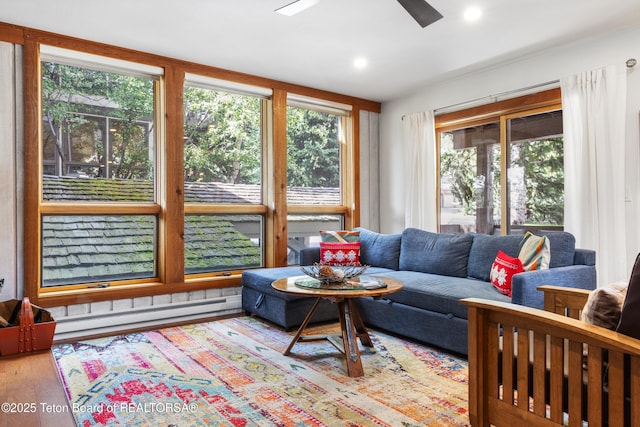 living room featuring a baseboard heating unit, hardwood / wood-style floors, and ceiling fan