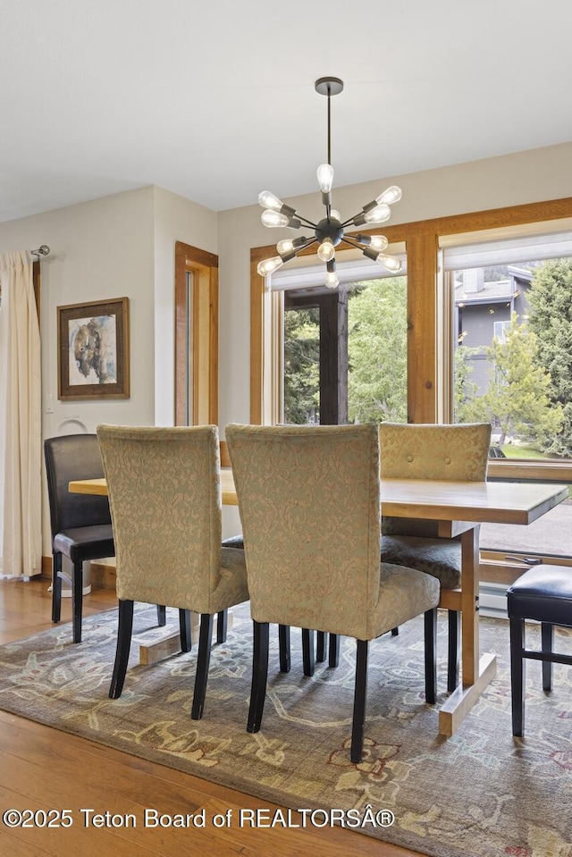 dining space with hardwood / wood-style floors and a notable chandelier