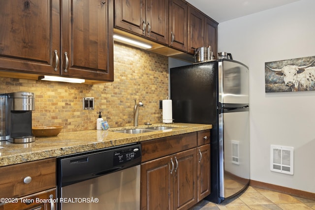 kitchen with sink, backsplash, stainless steel appliances, and light stone countertops