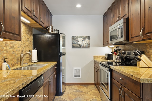 kitchen with stainless steel appliances, tasteful backsplash, sink, and light stone counters