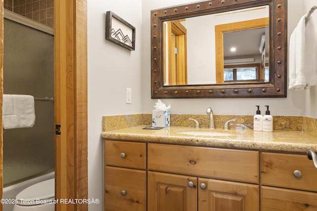 full bathroom featuring shower / bath combination with glass door, vanity, and toilet