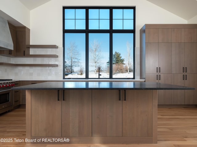 kitchen with high end range, a kitchen bar, vaulted ceiling, and light hardwood / wood-style flooring