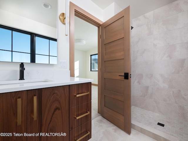 bathroom with tiled shower and vanity