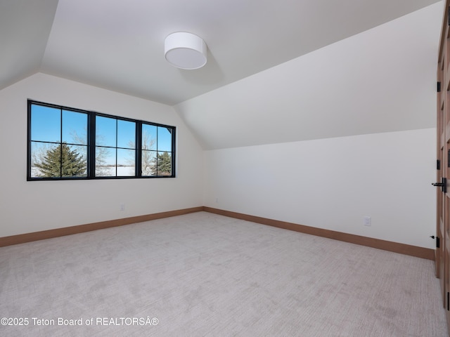 additional living space with vaulted ceiling and light colored carpet