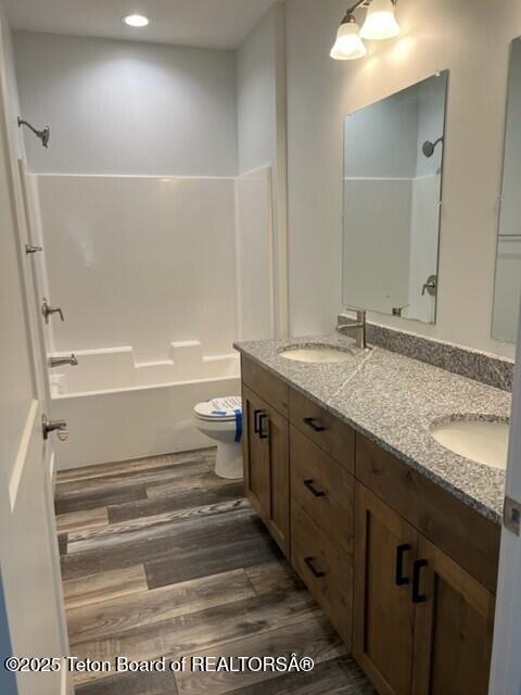 full bathroom featuring toilet, vanity, shower / washtub combination, and hardwood / wood-style floors