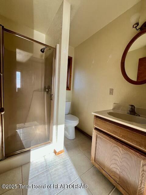 bathroom with toilet, vanity, tile patterned floors, and walk in shower