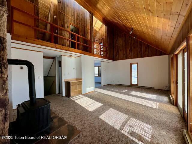 interior space featuring a wood stove, wood ceiling, high vaulted ceiling, and carpet