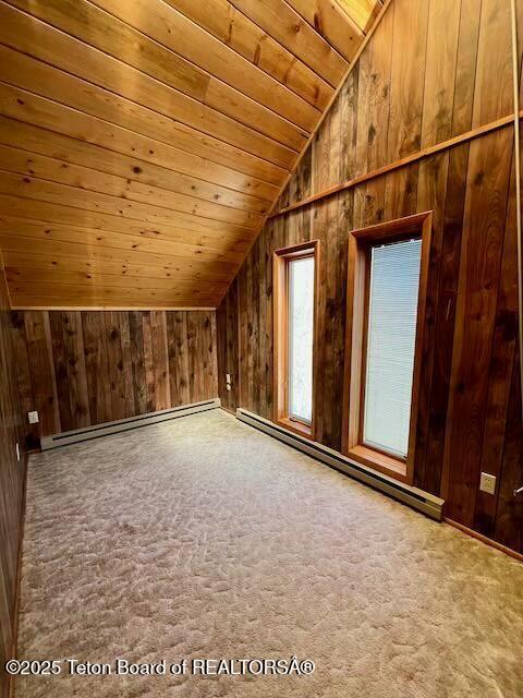 bonus room with wood walls, wooden ceiling, and a baseboard heating unit