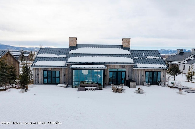 snow covered back of property featuring a mountain view