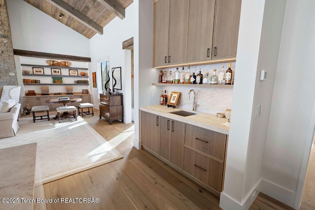 bar featuring sink, wood ceiling, backsplash, light hardwood / wood-style floors, and beamed ceiling