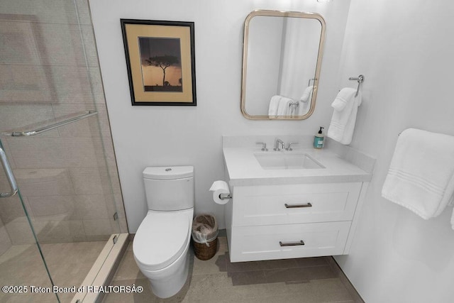 bathroom featuring vanity, tile patterned flooring, toilet, and tiled shower