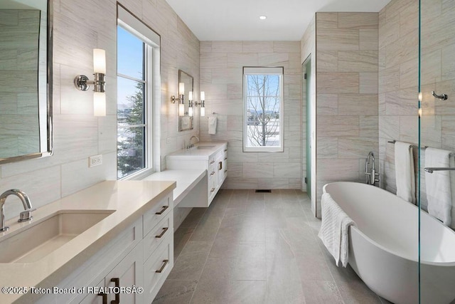 bathroom with vanity, independent shower and bath, and tile walls