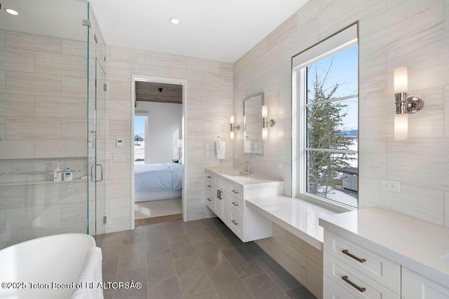 bathroom featuring vanity, plus walk in shower, and tile walls