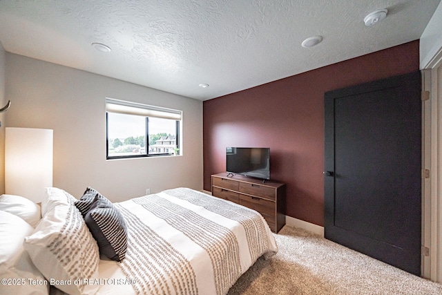 bedroom featuring light carpet and a textured ceiling