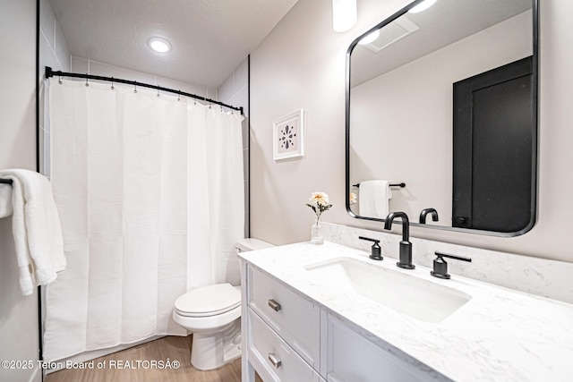 bathroom featuring wood-type flooring, vanity, and toilet