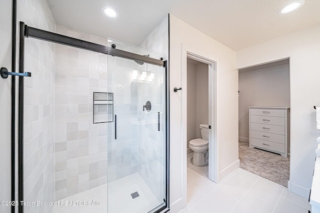 bathroom with tile patterned flooring, a shower with shower door, and toilet