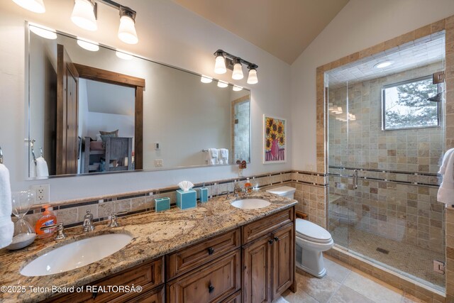 380 Cottongrass Rd, Driggs, ID 83422 - bathroom featuring tile walls, vaulted ceiling, double vanity, a stall shower, and toilet