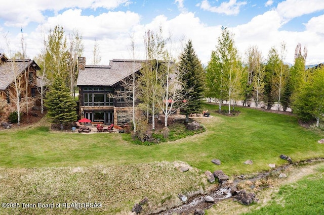 380 Cottongrass Rd, Driggs, ID 83422 - rear view of property featuring a yard, a chimney, a shingled roof, and a patio area