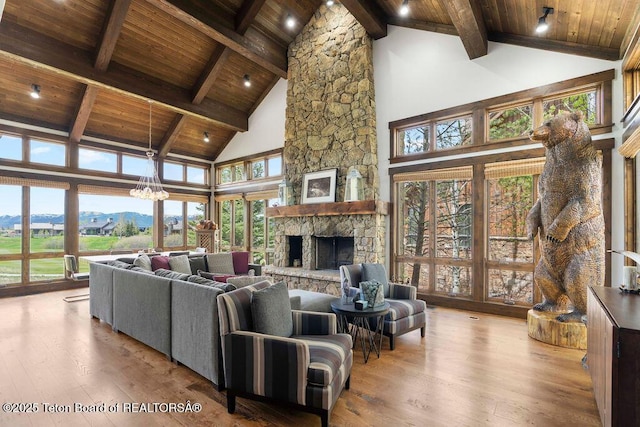 380 Cottongrass Rd, Driggs, ID 83422 - living area featuring wooden ceiling with exposed beams, high vaulted ceiling, hardwood / wood-style flooring, a stone fireplace, and a chandelier