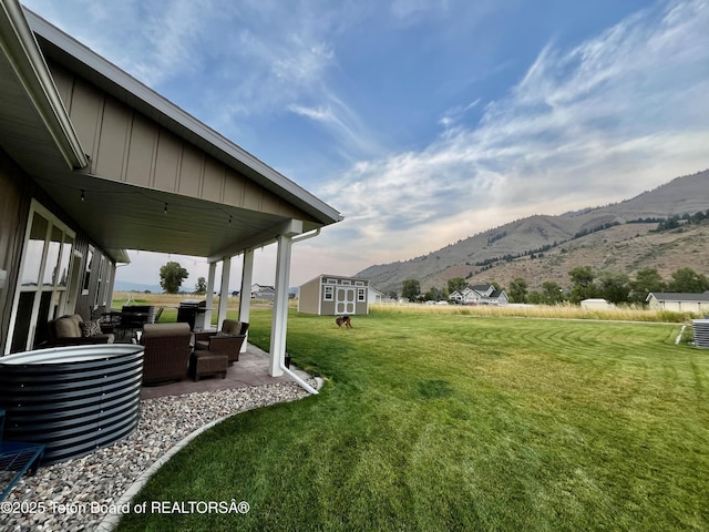 view of yard with a mountain view, a patio area, and a storage shed