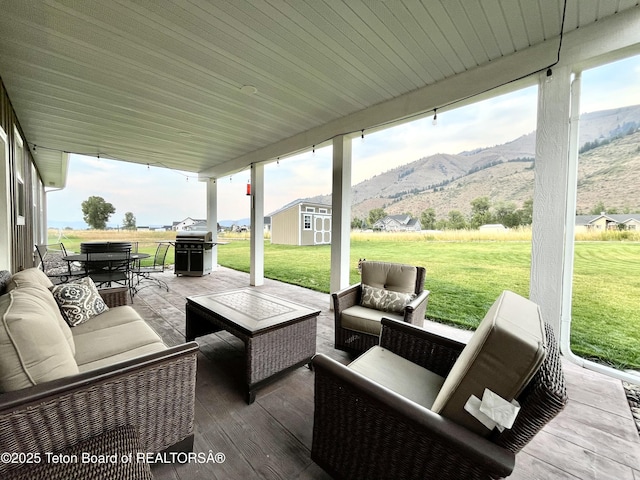 view of patio featuring area for grilling, a mountain view, an outdoor hangout area, and a storage unit