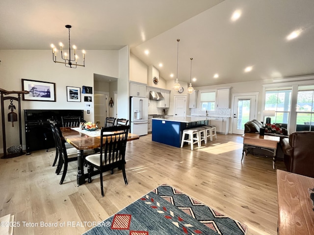 dining room featuring high vaulted ceiling, light hardwood / wood-style floors, and a chandelier