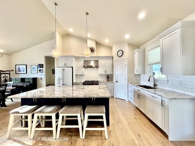 kitchen with a spacious island, white appliances, sink, and wall chimney exhaust hood