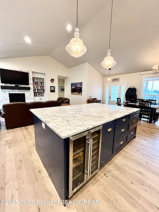 kitchen featuring wine cooler, hanging light fixtures, a center island, and light wood-type flooring