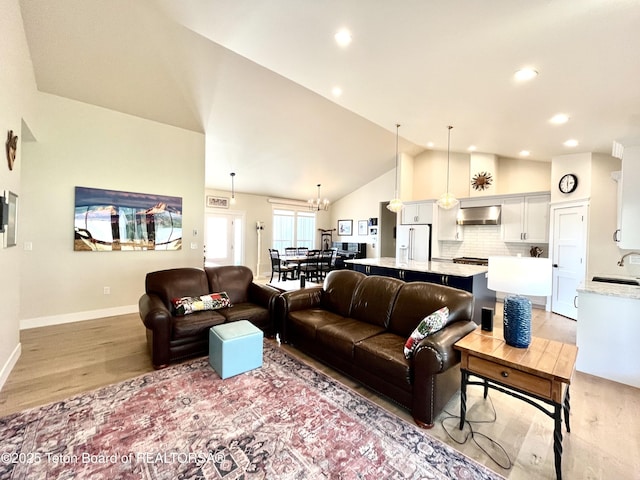 living room with sink, light hardwood / wood-style floors, and high vaulted ceiling