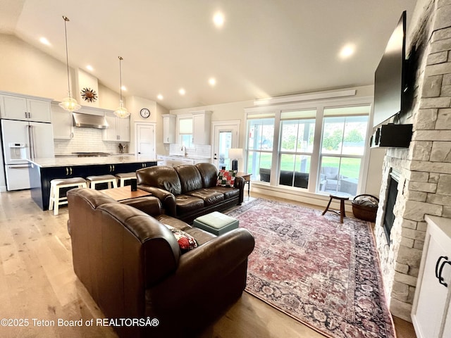 living room with sink, light hardwood / wood-style flooring, and high vaulted ceiling