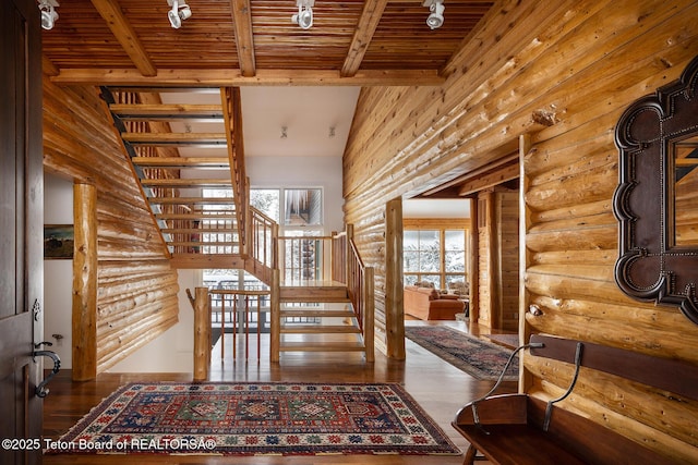 interior space featuring beam ceiling, log walls, rail lighting, wood ceiling, and wood finished floors