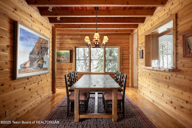 unfurnished dining area featuring a healthy amount of sunlight, wood walls, and beam ceiling