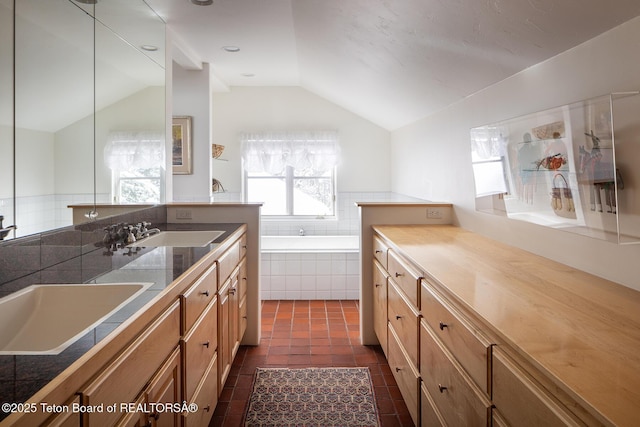 kitchen featuring lofted ceiling, dark tile patterned flooring, and a sink