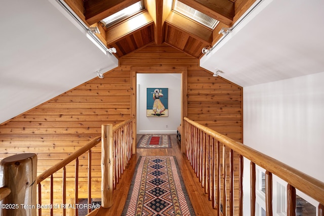 hallway with wood walls, vaulted ceiling with skylight, and hardwood / wood-style floors