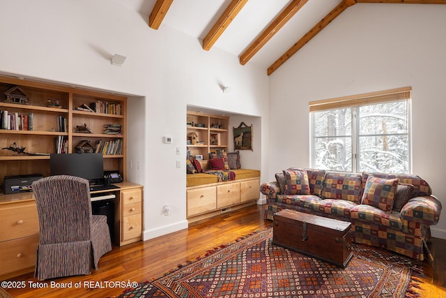 office area with beam ceiling, built in desk, wood finished floors, high vaulted ceiling, and baseboards