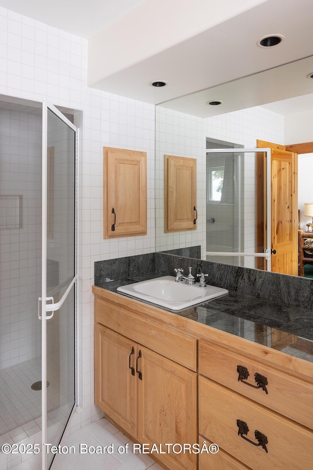 full bathroom with a stall shower, tile walls, vanity, and tile patterned floors