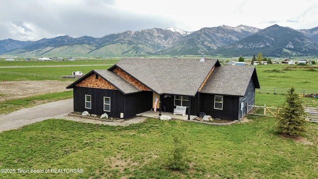 back of property featuring a mountain view, a yard, and a rural view