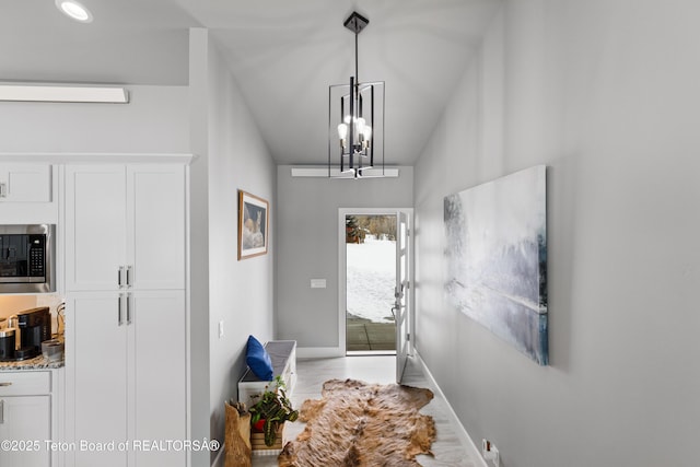 doorway to outside featuring an inviting chandelier and a wall unit AC