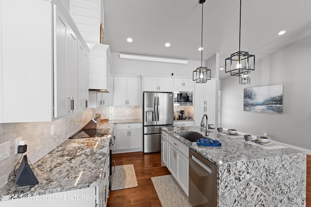 kitchen with sink, appliances with stainless steel finishes, pendant lighting, a kitchen island with sink, and white cabinets