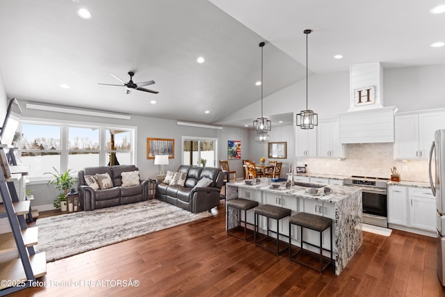 kitchen with a breakfast bar, white cabinetry, hanging light fixtures, a center island with sink, and appliances with stainless steel finishes