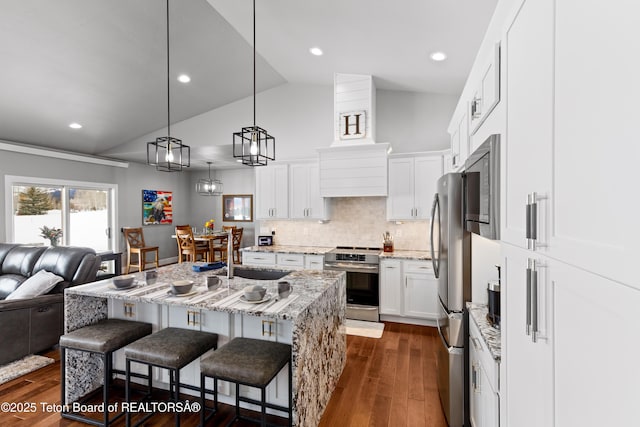 kitchen featuring sink, hanging light fixtures, an island with sink, stainless steel appliances, and white cabinets