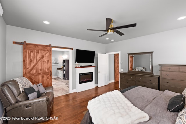 bedroom with hardwood / wood-style floors, a barn door, and ceiling fan