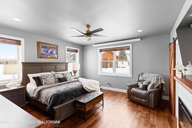 bedroom featuring a barn door, dark hardwood / wood-style floors, and ceiling fan