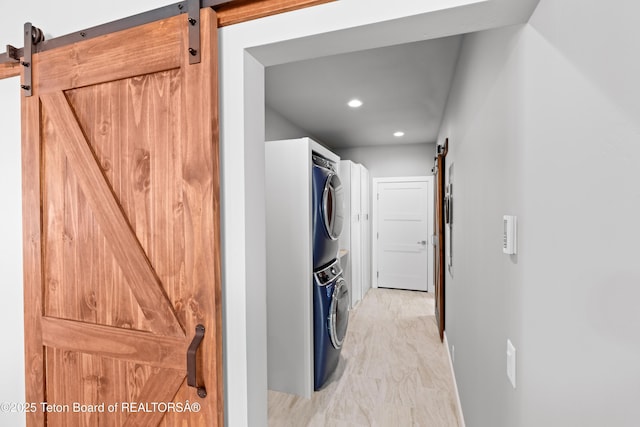 laundry area with stacked washer and clothes dryer and a barn door