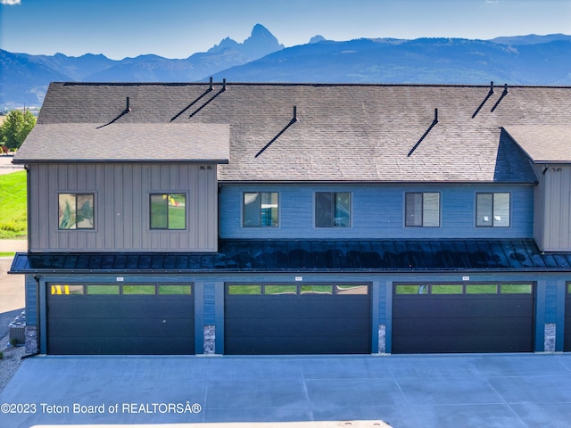 multi unit property with cooling unit, a garage, and a mountain view